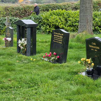 various tone gravestone sits in the grass of the emmerdale cemetary