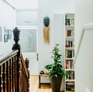 well-lit hallway with neutral-toned walls, featuring artwork and decorative accents