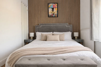 Upholstered double bed and bench, with bedside lamps and colourful art print