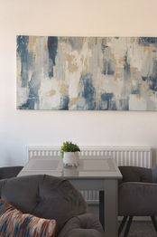 Dining table for two beneath a blue abstract canvas
