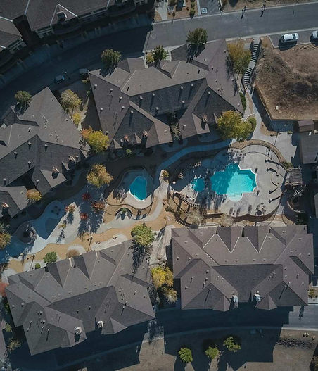 Aerial view of a well-maintained residential community featuring landscaped walkways, shared amenities, and a central swimming pool managed by a professional community association.