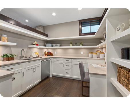 Spacious walk-in pantry with white cabinetry, open shelves displaying kitchen essentials, and a window for natural light, featured under the title "The Art of the Walk-In Pantry (& Why It’s a Game Changer)" with the Heartstone Custom Homes logo.