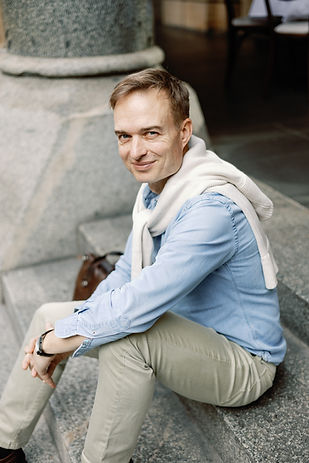 Olivier Vojetta sitting outdoors on stairs, looking up at the camera