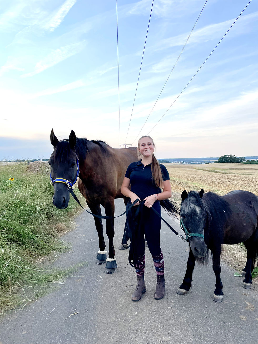 Nicole hält Pferd und Pony am Strick und lacht glücklich in die Kamera