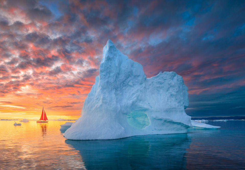 sailing under the midnight sun with amazing sky and red sail boat