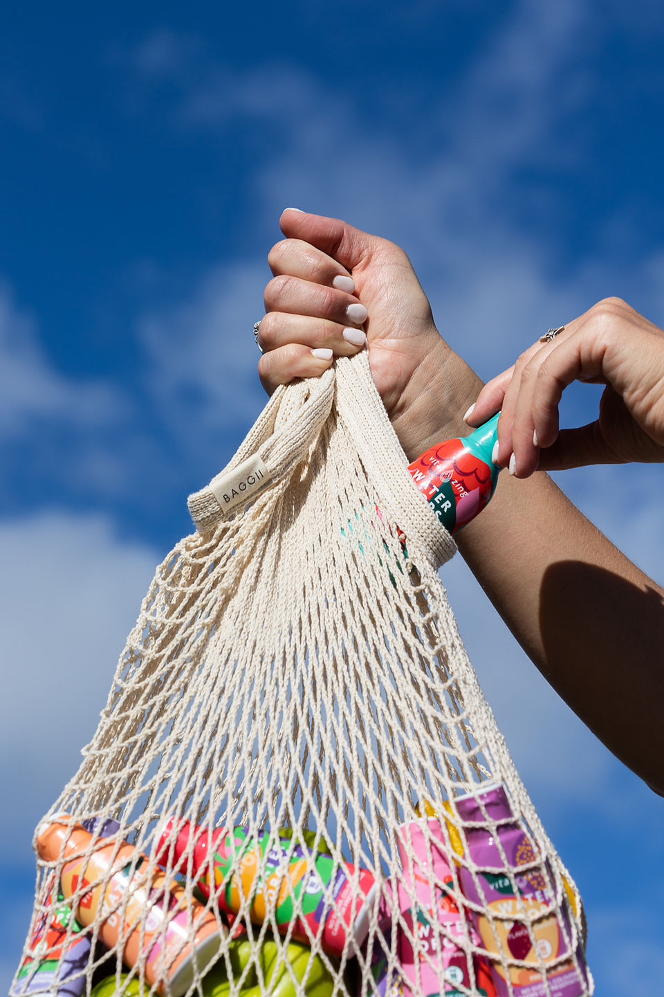 Water drop being placed in bag against blue sky.