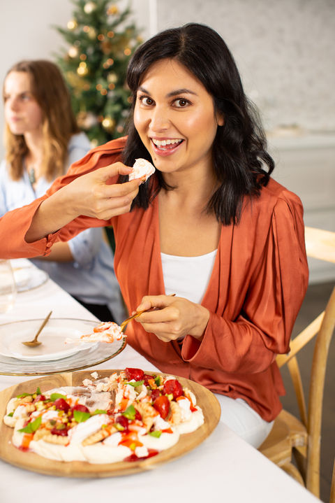 Nadia Lim trying a pavlova or Eton mess while smiling at the camera.