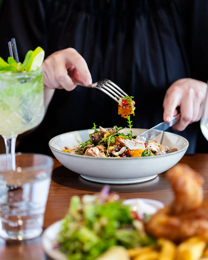 Someone digging into a pumpkin salad with knife and fork.