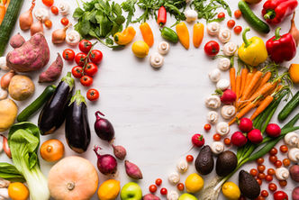 Flatlay of fresh vegetables arranged in the shape of a heart, featuring vibrant greens, tomatoes, carrots, peppers and a bunch more.