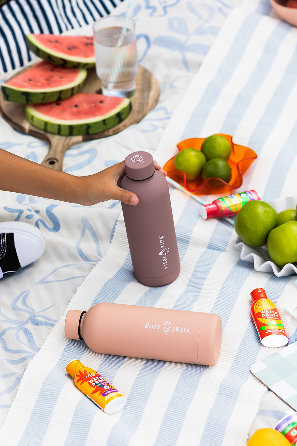 Water bottles on picnic blanket with fresh fruits.