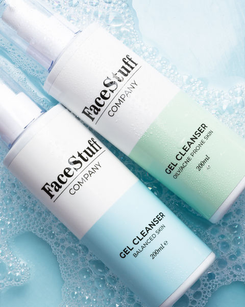 Two FaceStuff cleansers laying in blue water and bath bubbles.