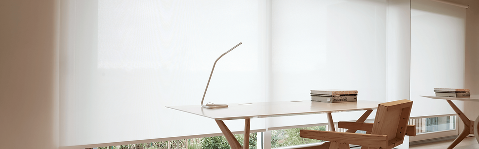 Minimalist office with a wooden desk and chair, a sleek lamp, books, and bright white blinds. Calm, well-lit atmosphere.