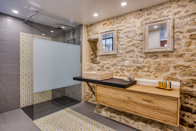 Salle de bain avec sa douche à l'italienne son lavabo en Travertin et son mur de pierres de Dordogne