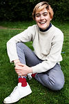 A girl is sitting on the grass smiling at the camera