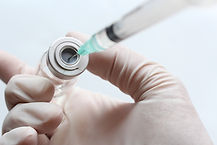 Mão enluvada a preparar injeção em frasco