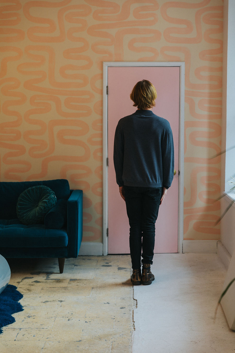 Men wearing black standing in a room covered with peachy wallpaper
