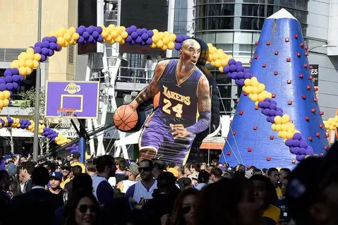 Large inflatable Kobe Bryant statue at a Lakers event, surrounded by purple and gold decorations.