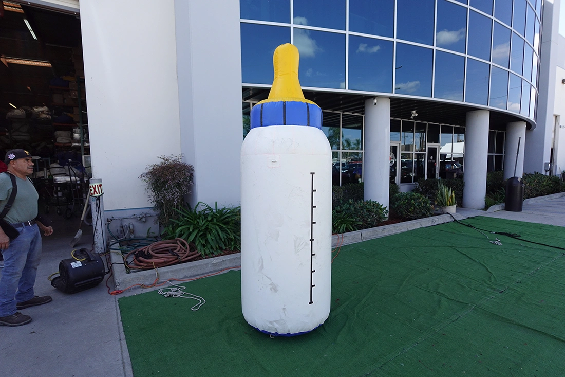 Giant inflatable baby bottle prop installed outdoors for event display and promotional use