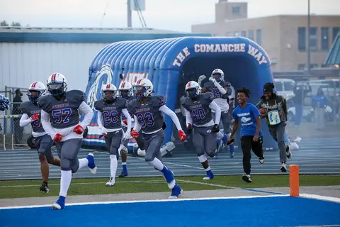 Football players running out of a custom inflatable team tunnel on game day.