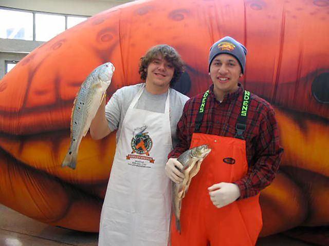 Seafood event participants holding fish in front of a giant inflatable crab
