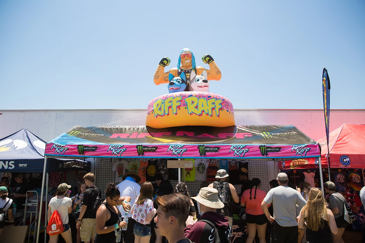 A colorful custom printed canopy featuring artist branding for RIFF RAFF, complete with a large inflatable topper showcasing the performer’s likeness. This pop up tent is used at a music or merchandise event to attract fans and create a standout booth experience.