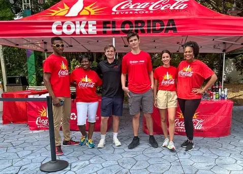 Coca Cola custom canopy tent with branded top and promotional staff at outdoor event.