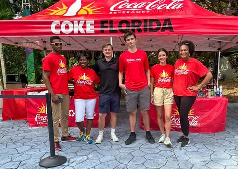 Coca-Cola 10x10 custom canopy tent with team posing at branded event booth