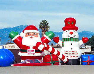Giant inflatable Santa Claus, snowman, and candy cane setup in front of a retail building for a holiday display