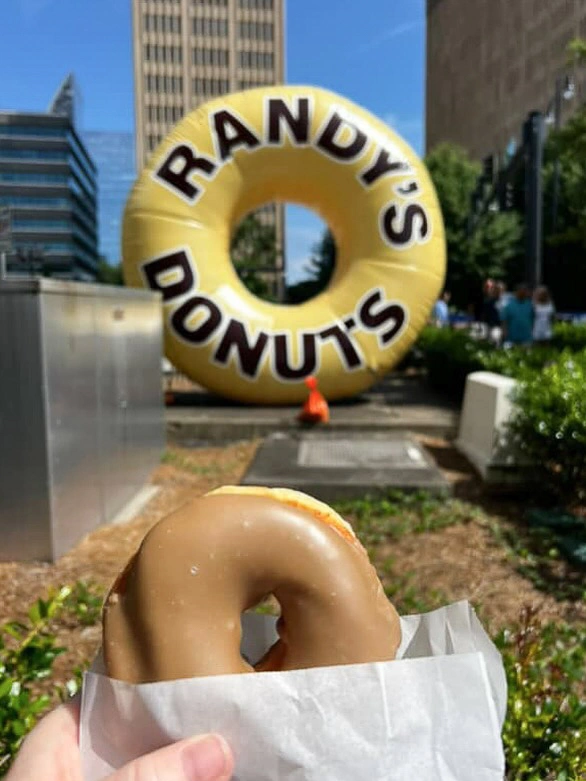 Close-up donut in foreground with giant inflatable donut replica displayed outdoors in the background