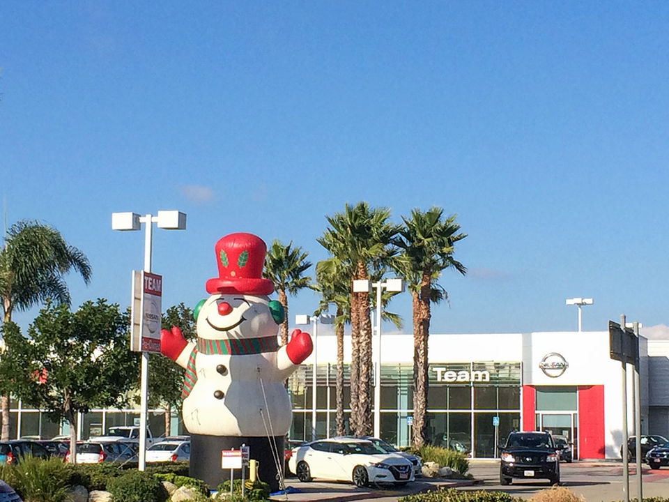 Large inflatable snowman rental set up near a car dealership, perfect for holiday promotions and winter events.