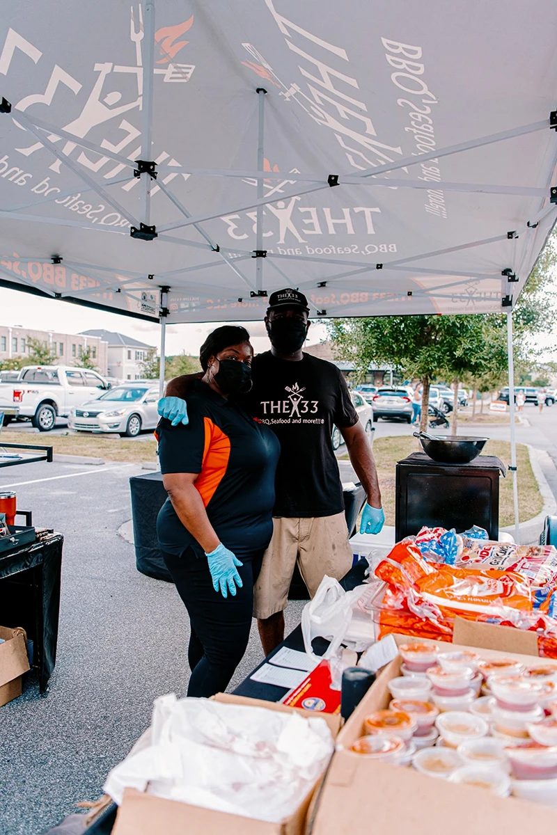 Restaurant staff standing under custom pop up canopy with food display for outdoor service.