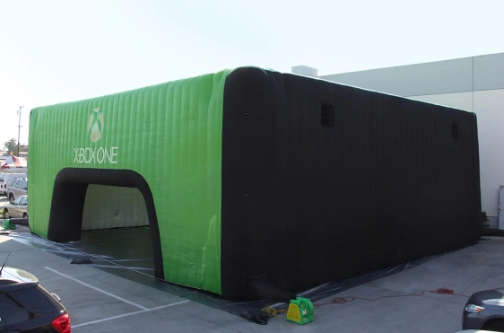 Black and green cube-style inflatable commercial tent with Xbox One branding and a wide arched entrance, set up outdoors.