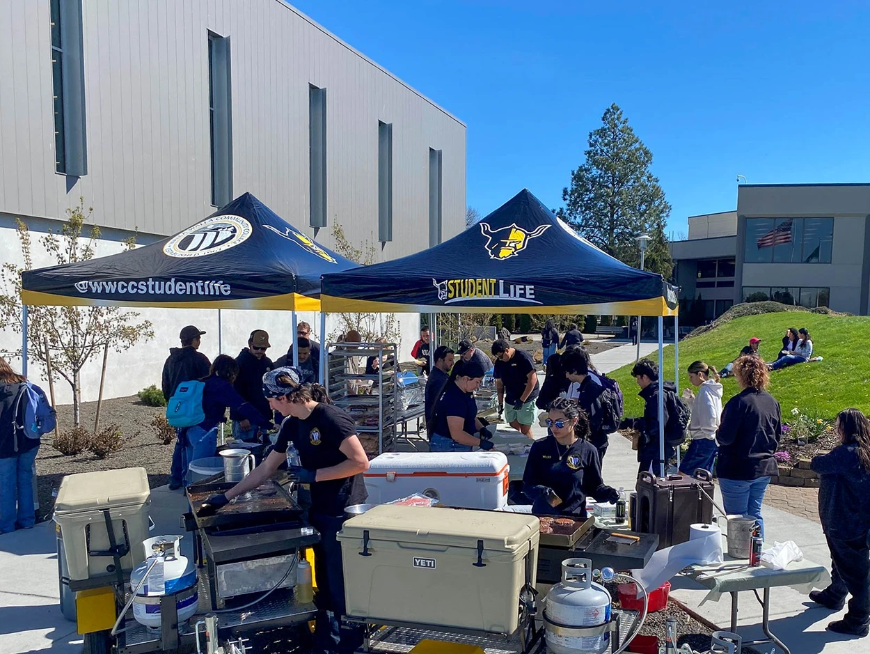 Heavy duty pop up canopies with student life branding used for a barbecue setup on a university campus.