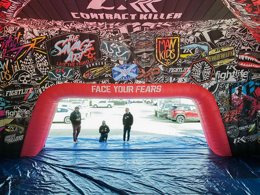 Interior view of an inflatable commercial tent with full printed graphics and a red arched entry opening, staged for an event activation.