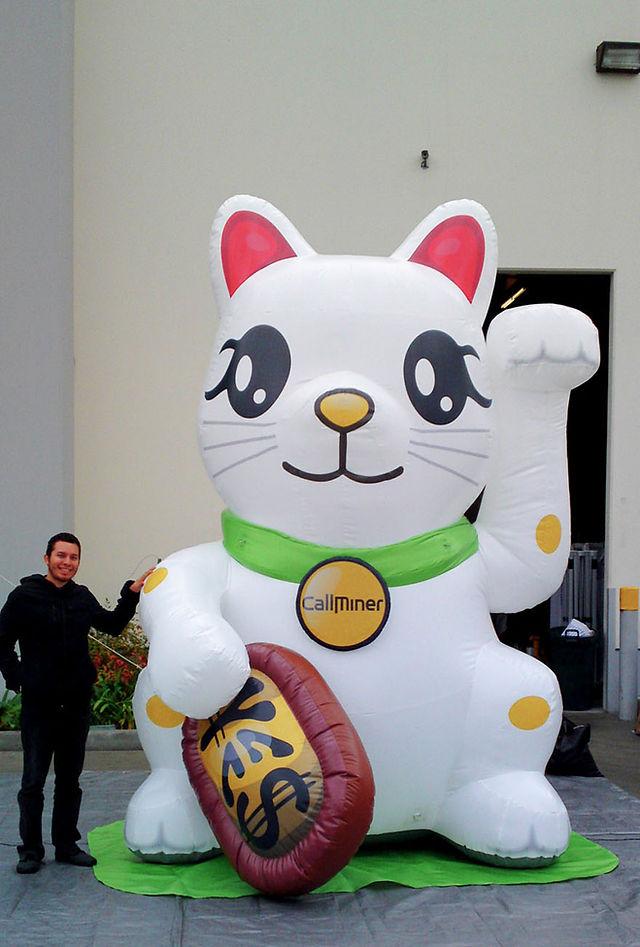 Custom white inflatable lucky cat with printed branding, green collar, raised paw, and decorative coin
