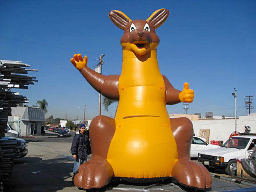 Front view of a giant brown inflatable kangaroo beside a person for scale