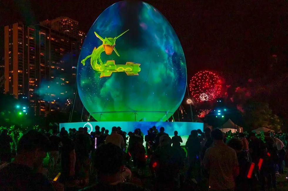 Giant inflatable sphere used for projection mapping outdoors with a large crowd watching and fireworks visible in the background.