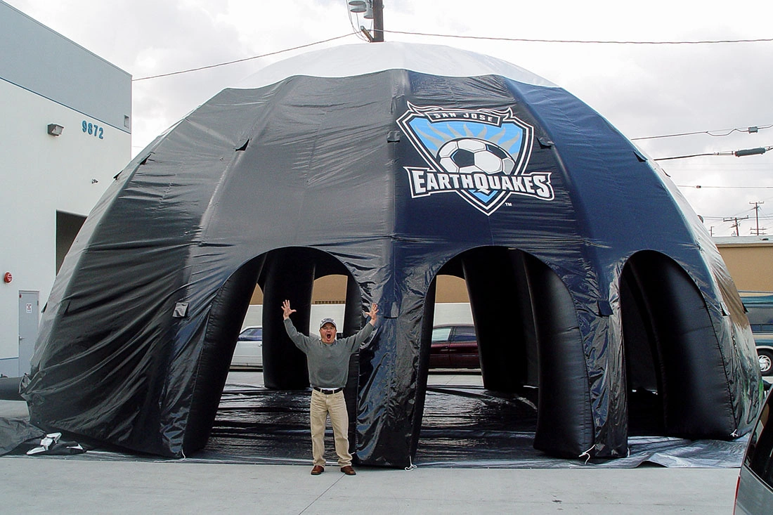 Black branded inflatable dome structure with multiple entry arches set up outdoors for a soccer fan zone activation.
