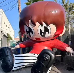 Large inflatable anime character displayed outdoors, featuring a seated design with vibrant colors.