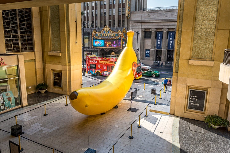 Giant inflatable banana installed in an outdoor plaza near a venue entrance, photographed from an elevated angle.