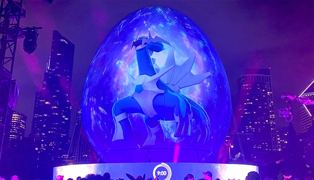 Projection mapped inflatable sphere at a nighttime event with animated visuals displayed on the surface and a crowd watching.