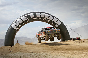 Black inflatable race arch branded with Method Race Wheels, framing an off-road truck in action.