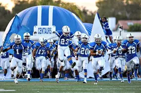 Football team rushing through a custom inflatable entrance tunnel at a school game.