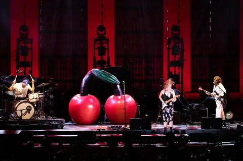 A pair of giant inflatable cherries on stage during a live concert performance, creating a unique stage design.