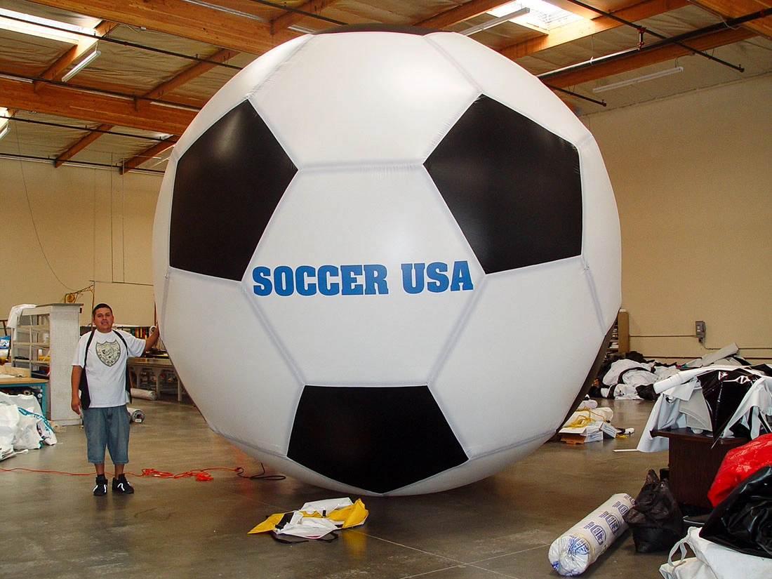 Branded inflatable soccer ball reading “SOCCER USA” inside a warehouse during setup and production.