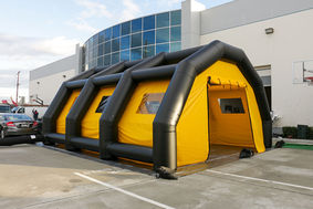 Black and yellow inflatable work tunnel set up outside a building.