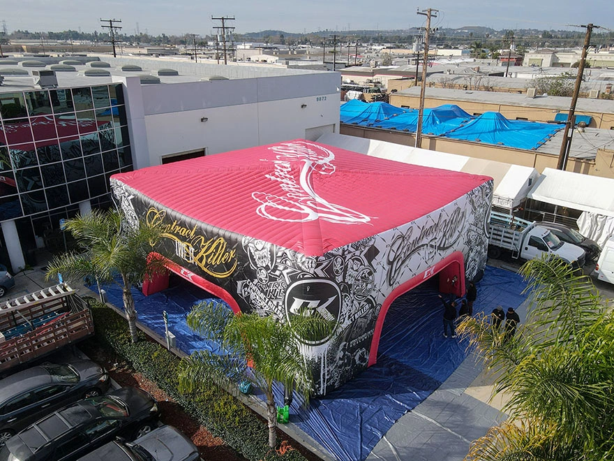 Aerial corner view of a 45x45 inflatable commercial tent with roof branding and multiple arched entrances, staged outdoors on tarps.
