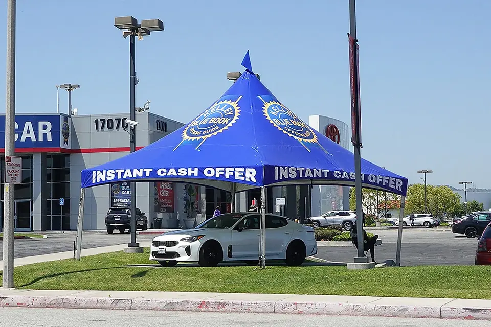 Blue high peak promotional tent with “Instant Cash Offer” branding used at a car dealership for outdoor advertising.