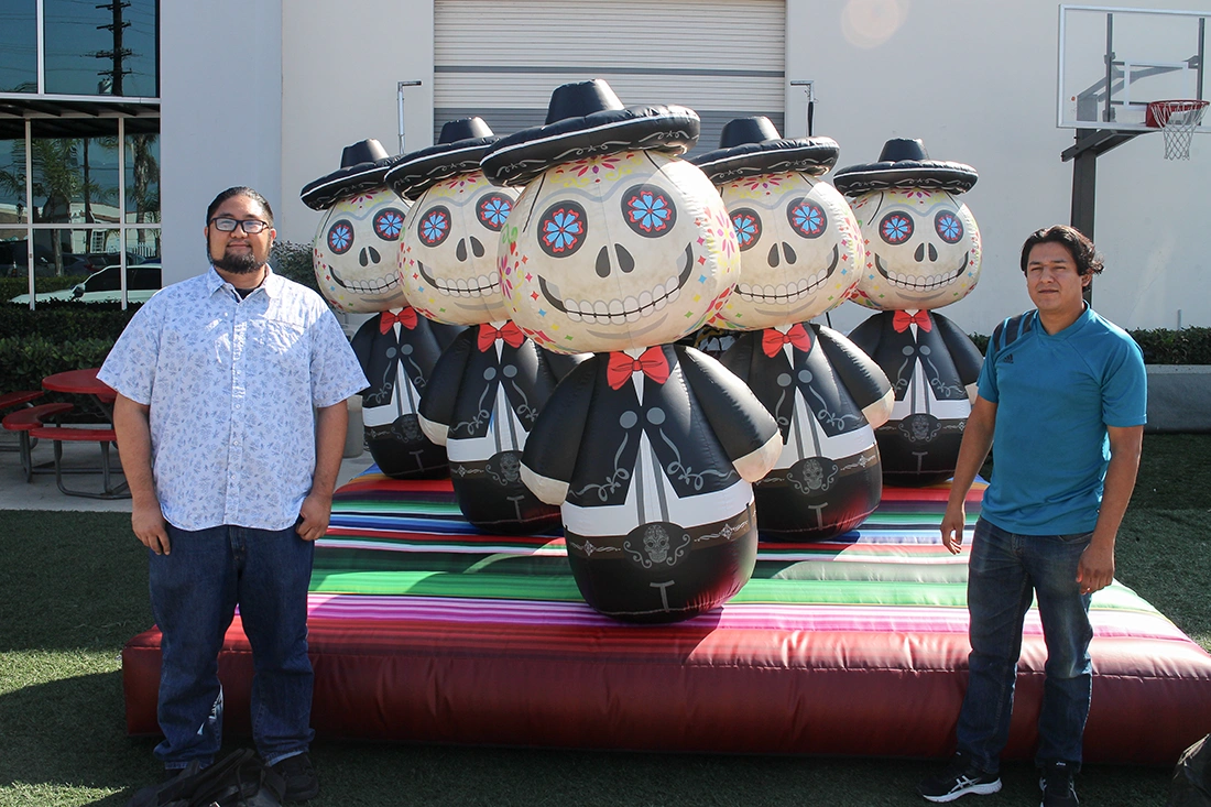 Themed inflatable ring toss game with multiple character targets on a colorful inflatable base, with two people standing in front for scale.
