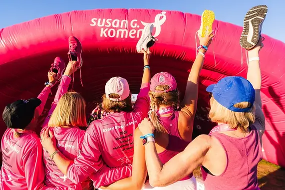 Large pink inflatable arch with Susan G. Komen branding at a charity race event.